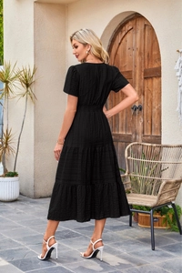 Detail of tiered skirt layers and elastic waist on a black short sleeve midi dress