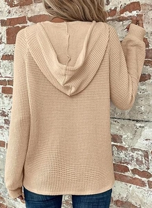 Rear view of a beige waffle knit hoodie featuring a fixed hood and ribbed cuffs on a model