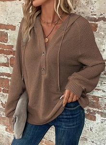 Detailed macro view of waffle knit fabric and button neckline on brown hooded shirt