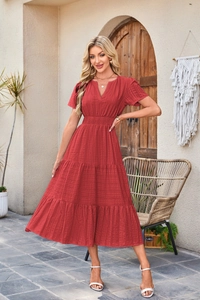 Detail of red tiered V-neck dress featuring a smocked high waist and textured fabric