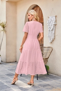 Dettaglio del ricamo sangallo rosa e dei balze su un abito midi femminile
