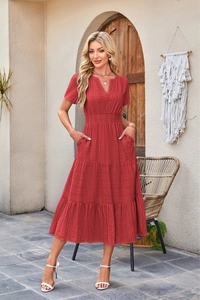 Detail of red V-neck tiered dress featuring puff sleeves and textured casual fabric
