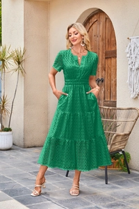 Dettaglio dell'abito verde con scollo a V, ricamo a occhielli e gonna a balze con tasche
