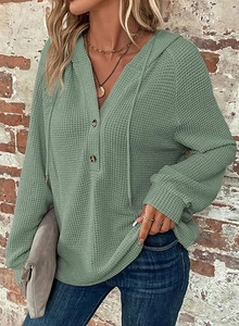 Detail of waffle knit fabric on sage green hoodie with V-neck button and drawstring