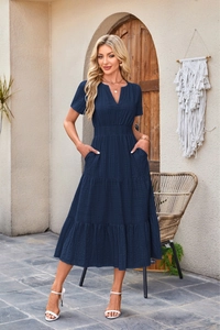 Detailed view of dark blue V-neck dress with puff sleeves and layered skirt texture