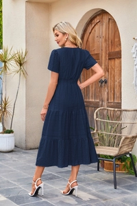 Detail of tiered midi dress featuring short sleeves and smocked waist in dark blue fabric