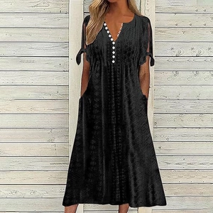 Close-up of V-neckline with white buttons and sleeve knot detail on a black dress