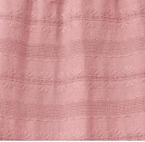 Close-up of mauve fabric featuring intricate hollow floral embroidery and cotton texture