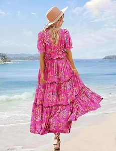 Detail view of pink bohemian floral dress with tiered skirt and puff sleeves on beach