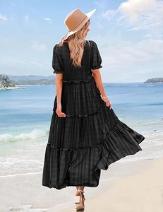 Back view of puff sleeve black and green checkered tiered dress on a sunny beach