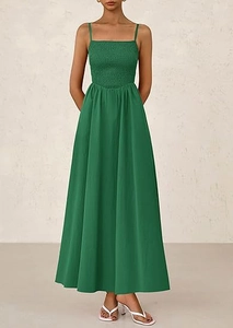 Full body view of dark green smocked dress with thin straps and flowy skirt