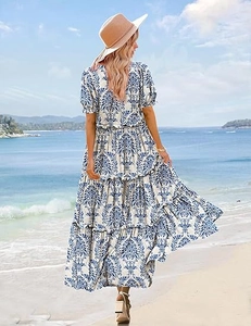 Outdoor view of tiered printed maxi dress with blue floral pattern against beach background