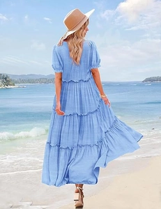 Sky blue tiered maxi dress with puff sleeves and ruffled hem on a sunny beach background