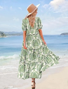 Rear view of printed tiered maxi dress with green floral patterns on a sunny beach