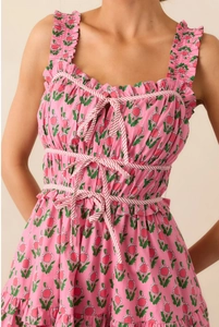 Detailed view of pink floral dress with ruffled straps and red striped bow ties
