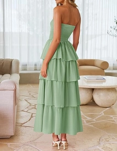 Detail view of smocked bodice and tiered layers on a light green strapless maxi dress