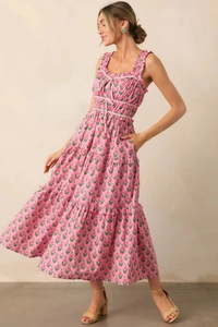 Detail of floral tiered maxi dress with ruffled straps and bow accents in soft pink