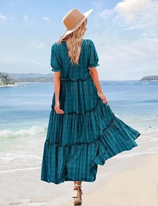 Detail of a dark green plaid tiered maxi dress with ruffles against a beach backdrop