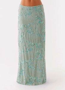 Close-up of sequin floral embroidery and beaded detailing on a green long skirt