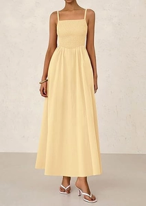 Detail view of smocked bodice and delicate spaghetti straps on a light yellow maxi dress