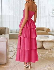 Detail view of fuchsia smocked strapless tiered maxi dress on a model in a home setting