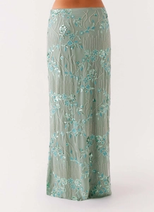 Macro detail of intricate sage green beadwork and sequin floral embroidery on a maxi skirt