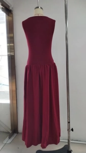 Detail of burgundy sleeveless maxi dress featuring a gathered waist and draped flowy hem