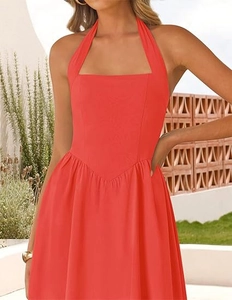 Close-up of vibrant coral halter neck dress with V-shaped waist seam and pleats