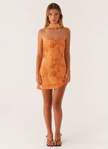 Detailed close-up of warm orange sequined embroidery and floral beadwork on a mini dress
