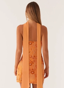 Close-up of orange sequin mini dress back featuring long chiffon streamers and floral beadwork