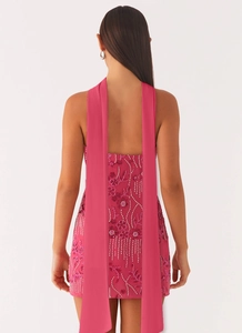Detail of rose pink sequin embroidery and long chiffon ribbons on the back of the mini dress
