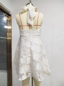 Detail of white halter dress featuring 3D rose jacquard fabric and a large back bow