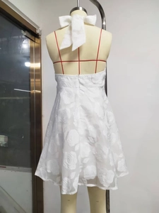 Detail of white halter mini dress featuring a large back bow and 3D rose jacquard fabric