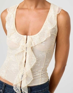 Gros plan détaillé du gilet en dentelle beige avec col en V, volants et fermeture à crochets