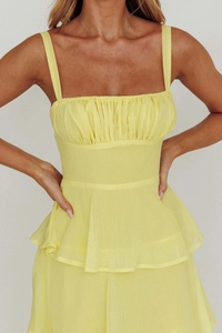 Detailed close-up of yellow backless tiered dress featuring pleated bodice and ruffled hem