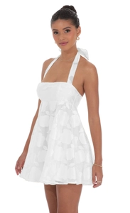 Detail of white halter-neck dress with floral jacquard fabric and back bow-tie design
