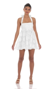 Detail of white halter neck mini dress featuring textured floral fabric and a large bow