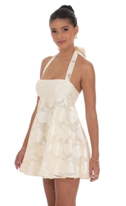 Detailed macro view of the cream-white floral jacquard fabric and halter neck dress design