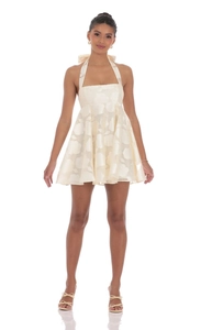 Close-up of cream halter dress featuring elegant floral jacquard fabric and back bow tie