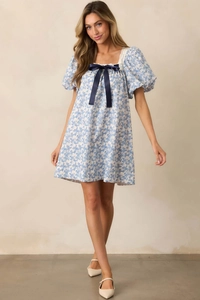 Detail of floral puff sleeve dress with square neck, lace trim, and blue silk bow accent