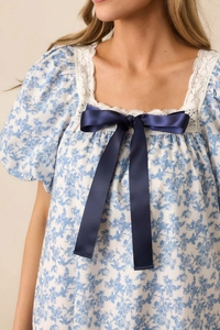 Detail of square neckline with lace trim and large navy satin bow on floral dress