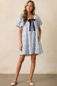 Detailed view of square neck dress with lace trim and dark blue ribbon bow accent