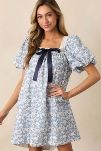 Detail of square neckline with lace trim and large dark blue bow on floral dress