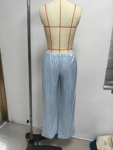 Détail du pantalon large à paillettes bleu clair montrant la texture métallique et le drapé