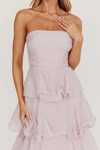 Dettaglio dell'abito a fascia rosa pallido con texture increspata e gonna a balze