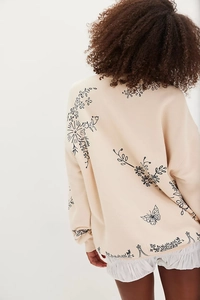 Rear view of beige knitted sweater featuring artistic black floral and butterfly patterns