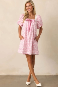 Close-up of pink floral dress featuring lace trim square neck and satin bow detail