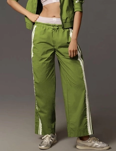 Detail view of olive green wide-leg track pants with side stripes and lace trim texture