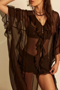 Detail of sheer black chiffon blouse with delicate ruffled edges and layered necklace