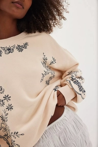 Detail of embroidered black butterflies and flowers on cream long sleeve sweatshirt